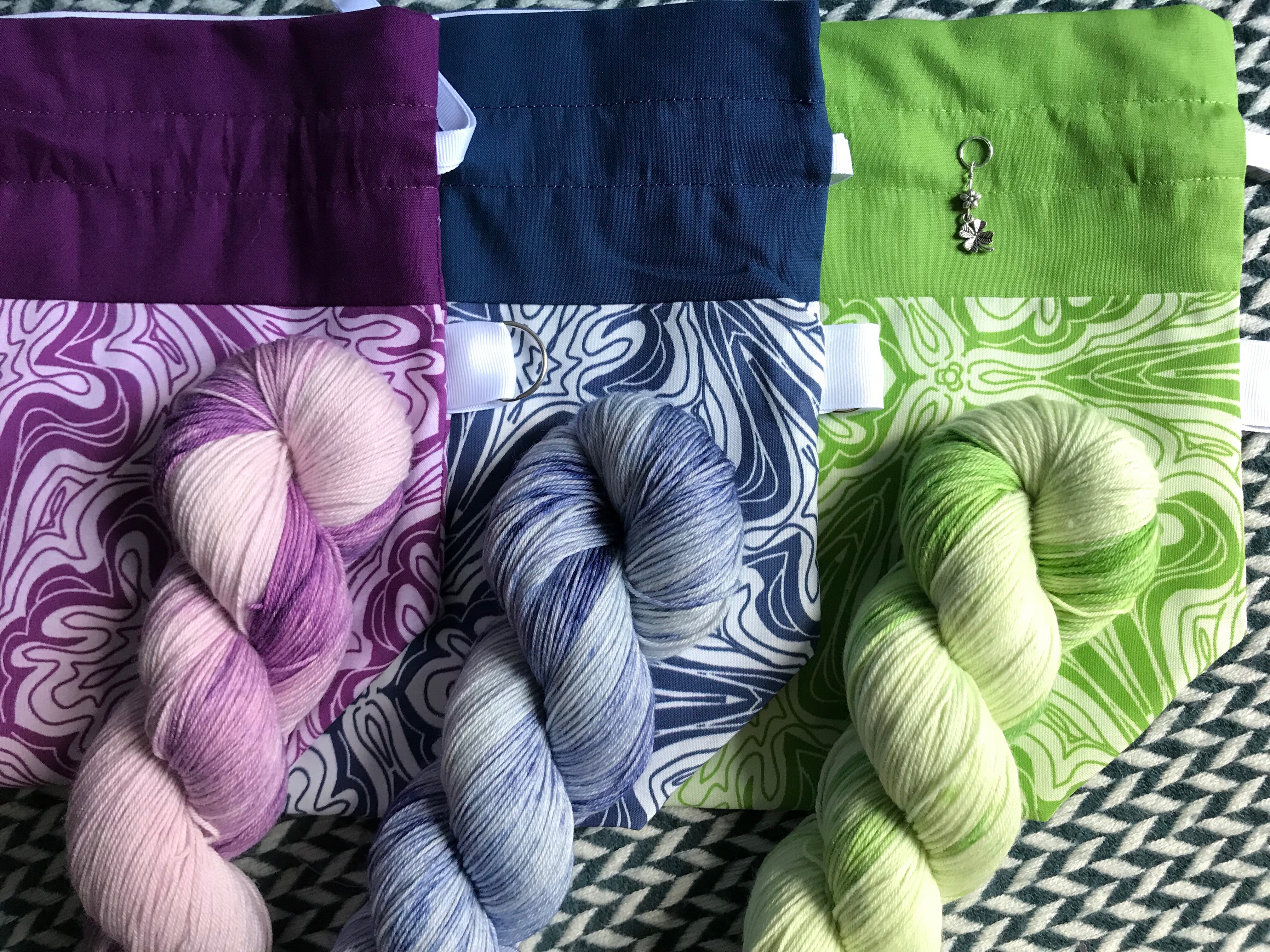 Three drawstring bags with three matching skeins of yarn
