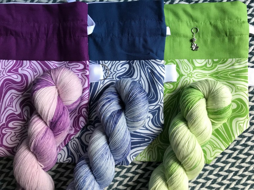 Three drawstring bags with three matching skeins of yarn